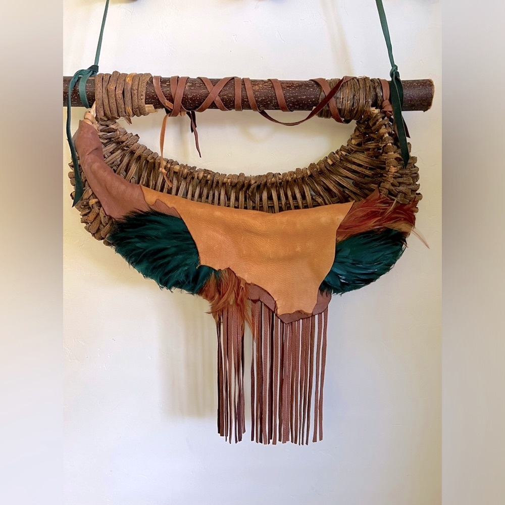 Handmade leather and wood basket weave with fringe and feathers.